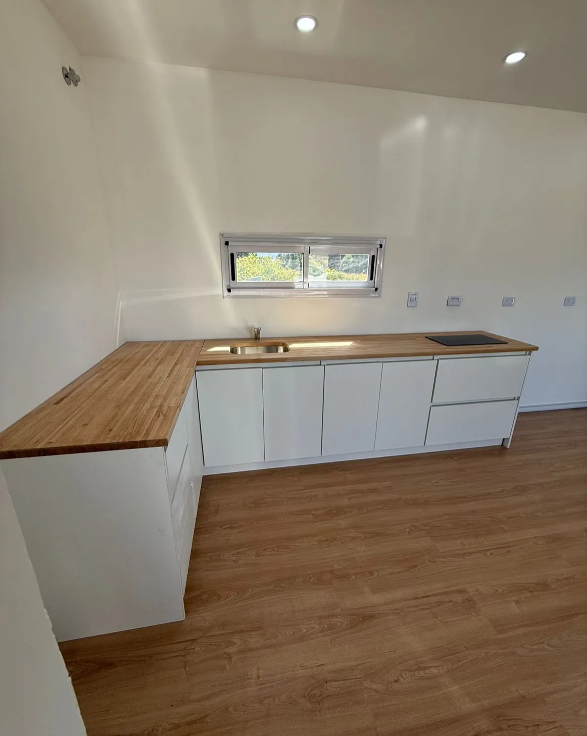 Cocina en L con mesada de madera de una casa container en Bariloche