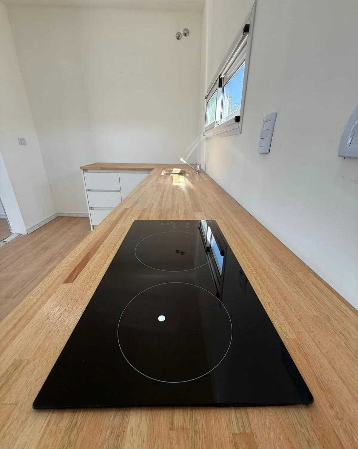Mesada de madera con anafe vitrocerámico en una casa container